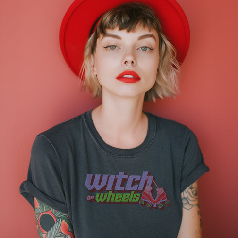 Gray t-shirt with "Witch on Wheels" text in purple and green, featuring a red roller skate graphic. The vintage-style design has a slightly faded look on a relaxed-fit unisex tee.
